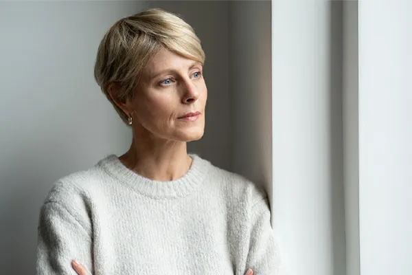 Chronic-Fatigue-Therapy A blond, middle-aged woman looks out the window with a tired expression. Get chronic fatigue treatment from Tanya Zboril, NP of TBT Medical in Halifax.