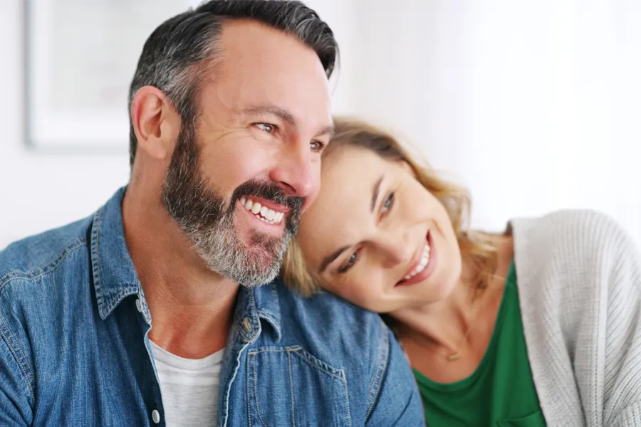 A middle-aged white couple in a bright white room smile and lay their heads on each other. Schedule concierge health and wellness services from Tanya Zboril, NP of TBT Medical in Halifax.