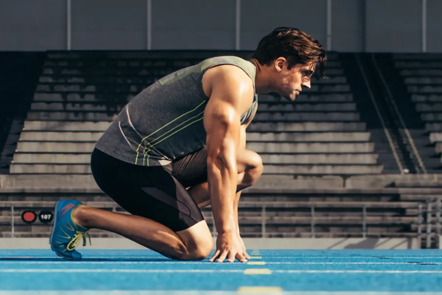 Lean-Muscle-and-Recovery-Clinic A white man kneels at the starting line on a track, determined to do his best. Get treatment for lean muscle loss and recovery from Tanya Zboril, NP of TBT Medical in Halifax.
