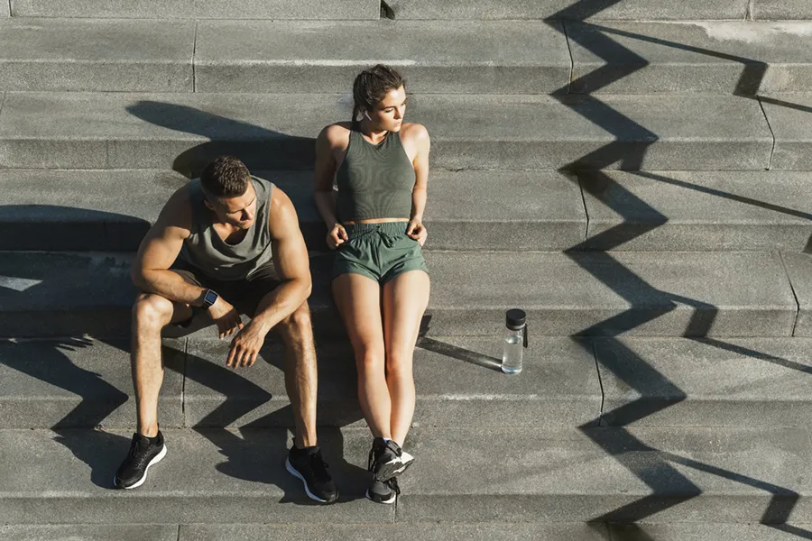 Medical-Weight-Loss-Doctor A couple in gray and green track clothes resting after a workout on stone steps, happy with their weight loss plans from Tanya Zboril, NP of TBT Medical in Halifax.