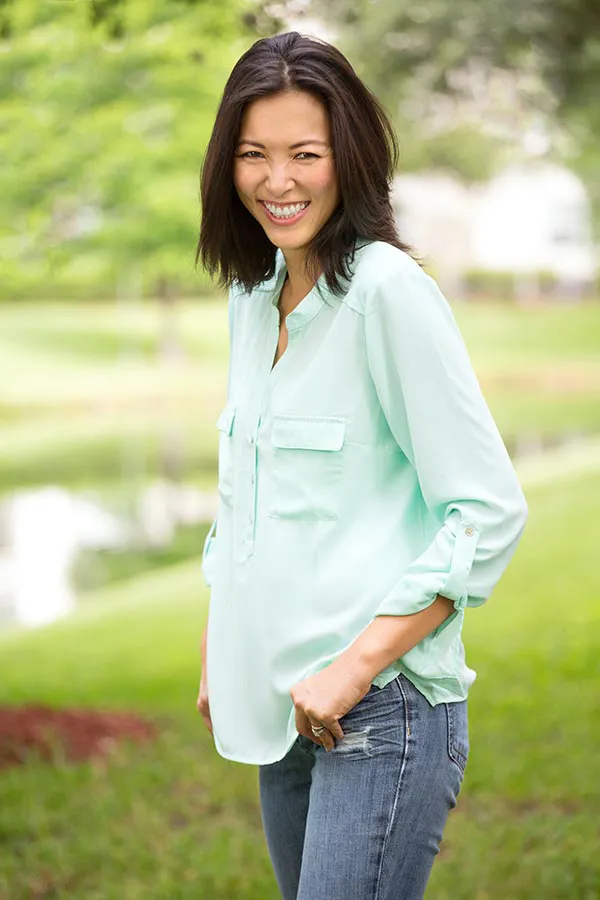 Perimenopause-Treatment A middle-aged brunette woman in a light green button-up shirt stands outside smiling, happy with her perimenopause treatment from Tanya Zboril, NP of TBT Medical in Halifax.