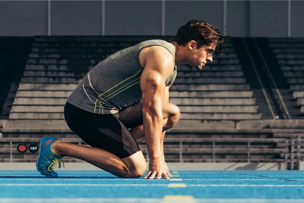 Sermorelin-Clinic With a determined look, Aamuscular man in track clothes kneels at the start of a race. Get Sermorelin peptide therapy from Tanya Zboril, NP of TBT Medical in Halifax.