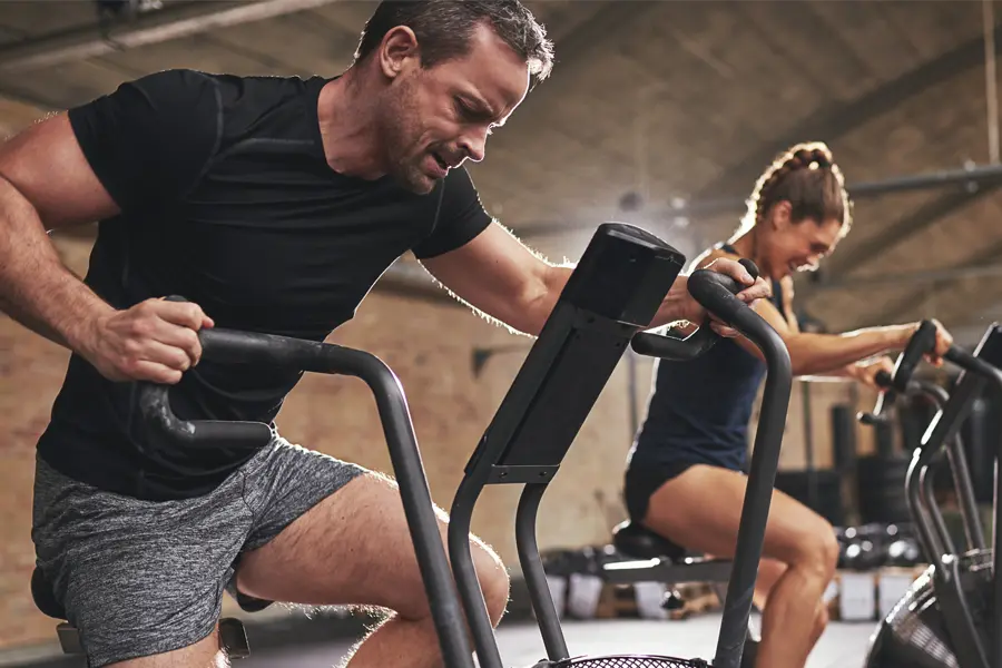 Tirzepatide-Doctor A couple in a brick gym work as hard as they can on exercise bikes, inspired by successful Tirzepatide treatment from Tanya Zboril, NP of TBT Medical in Halifax.